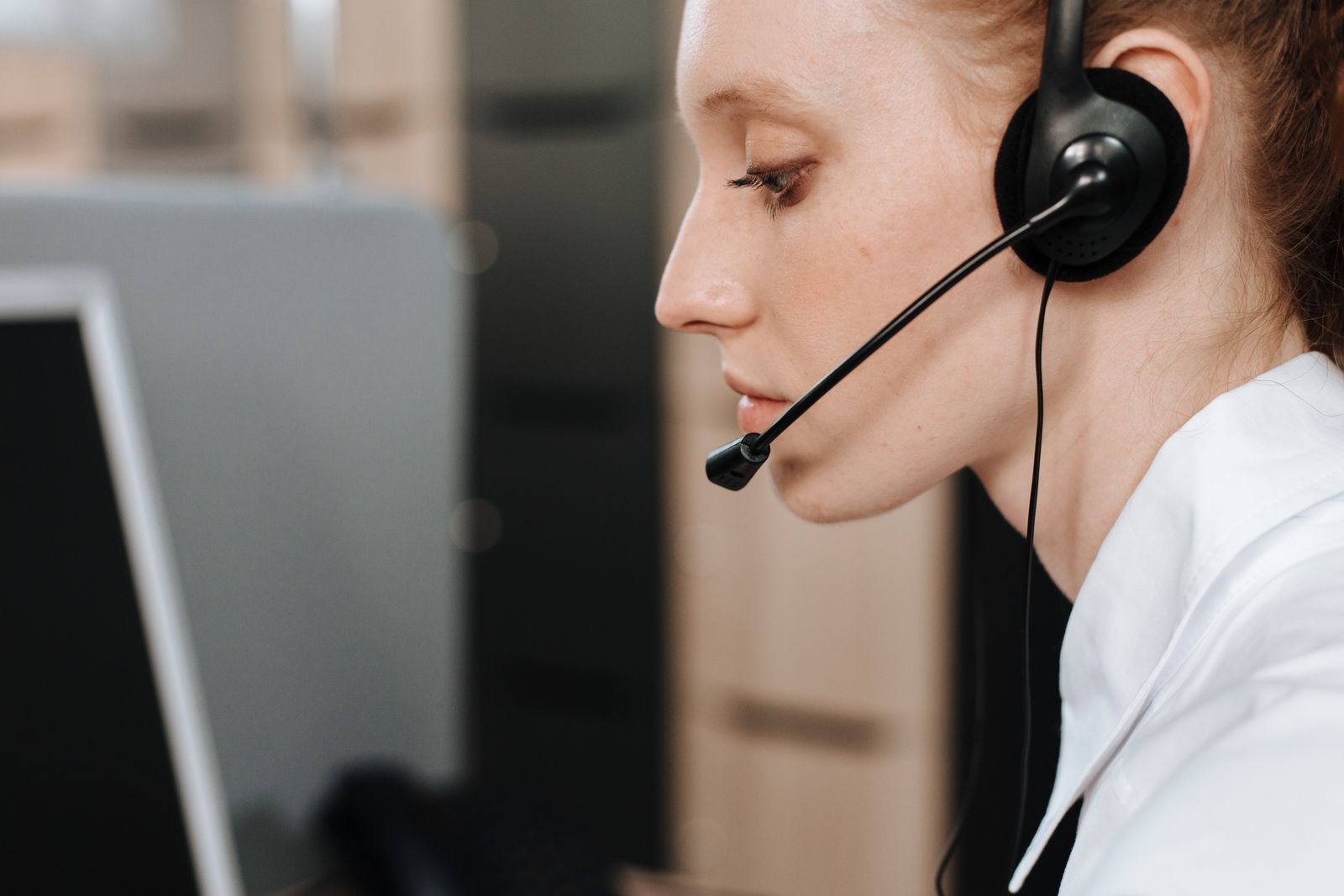 Contact centre agent on a headset handling a call at a workstation