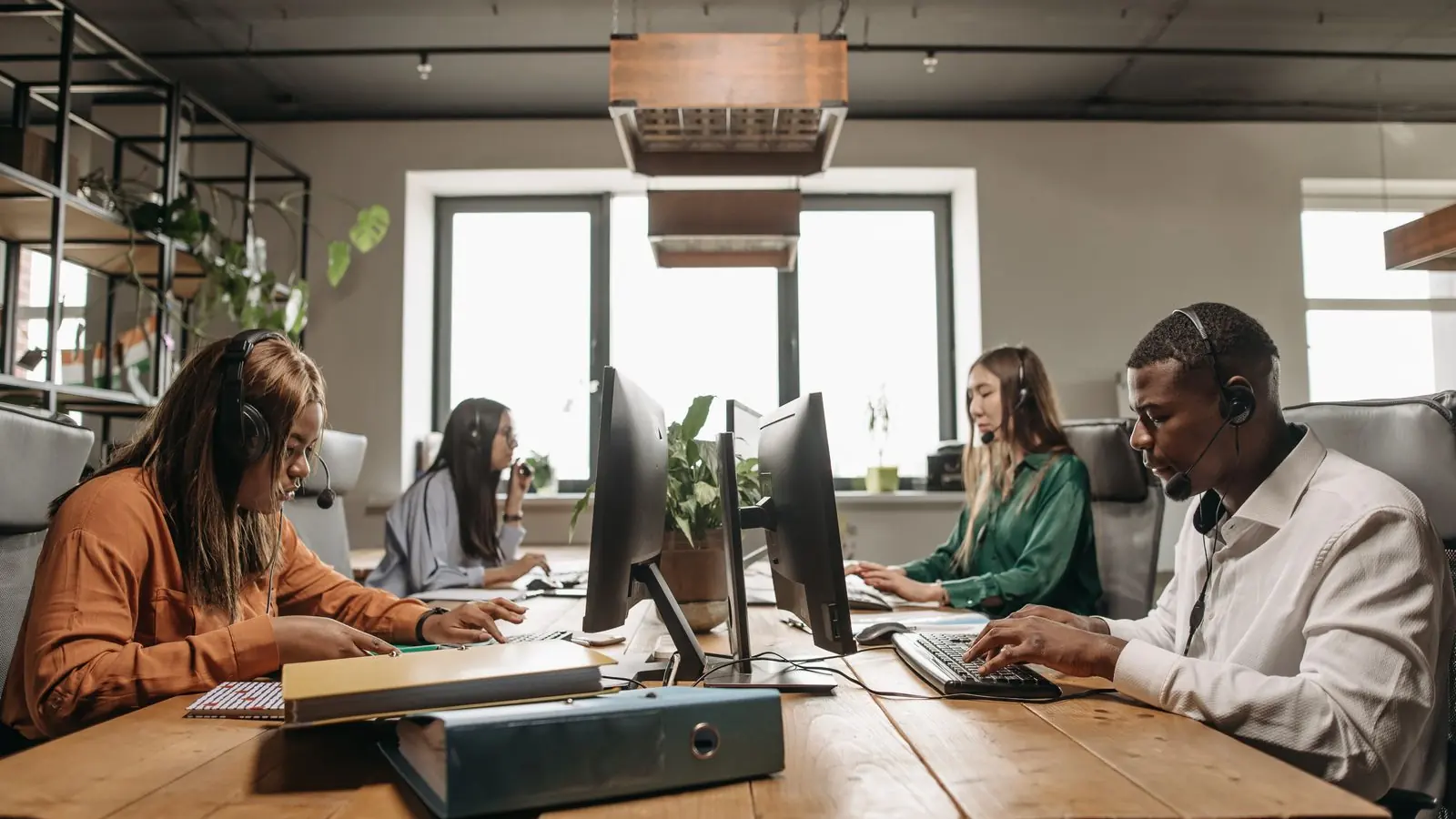 Contact centre team working at desks with headsets in a modern open-plan office